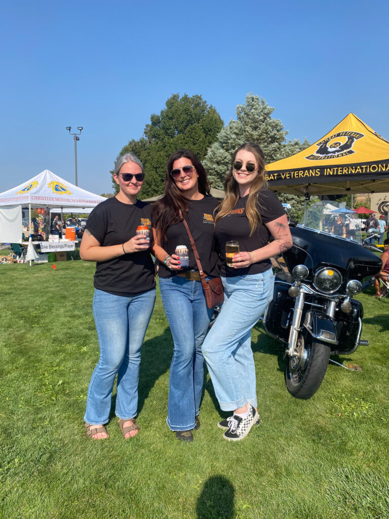 Three women at motorcycle event with bike