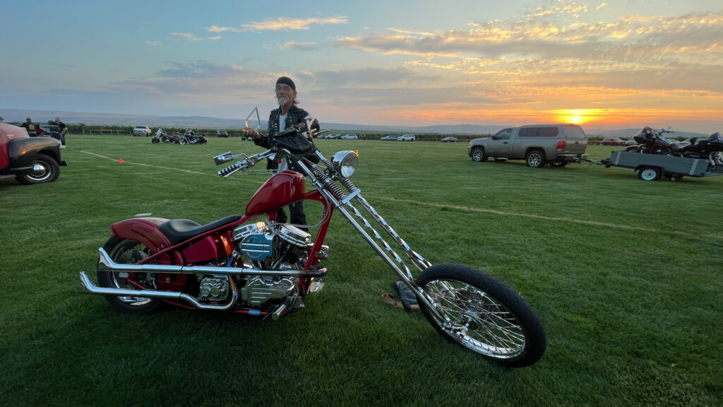 Man with custom chopper motorcycle at sunset